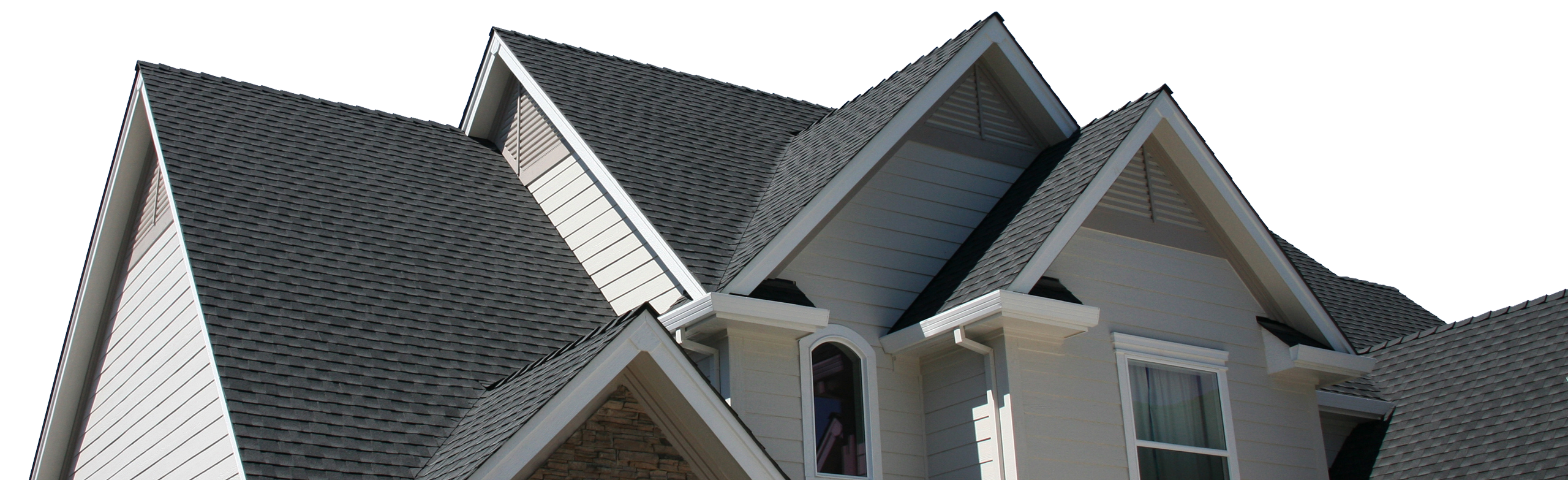 A close-up of a light-colored house with dark shingles and white trim under a bright sky.