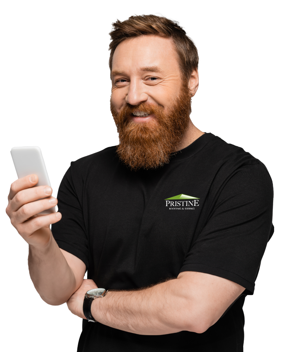 A smiling bearded man in a branded t-shirt holds a smartphone while looking at the camera.